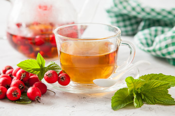 tea with a hawthorn and mint in a cup on a table, selective focus