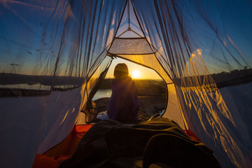 women sit front of tent with sunrise