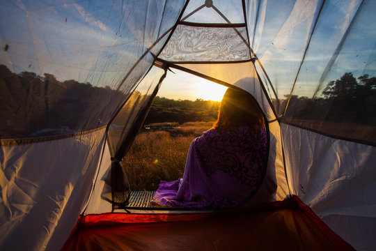 Fototapeta women sit front of camping tent glow up with sunrise in morning