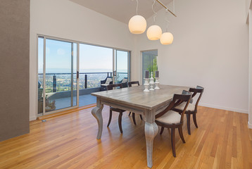 Elegant dining table and chair with open sliding doors leading to outdoors. 