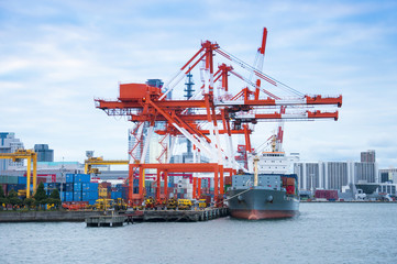 Fototapeta premium Commercial delivery cargo container ship being unloaded in the h