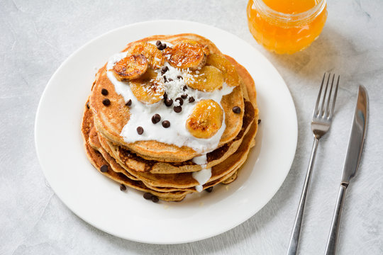 Corn pancakes with caramelized banana, natural yogurt and chocolate chips. Delicious whole grain pancakes. Healthy breakfast with homemade pancakes