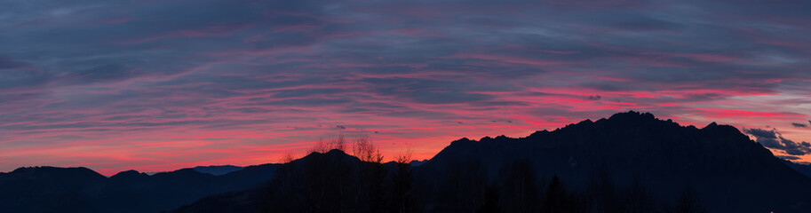 Fiery sunset from mountain pick in a cloudy evening. Fall season. Orobie mountains. Italian Alps.