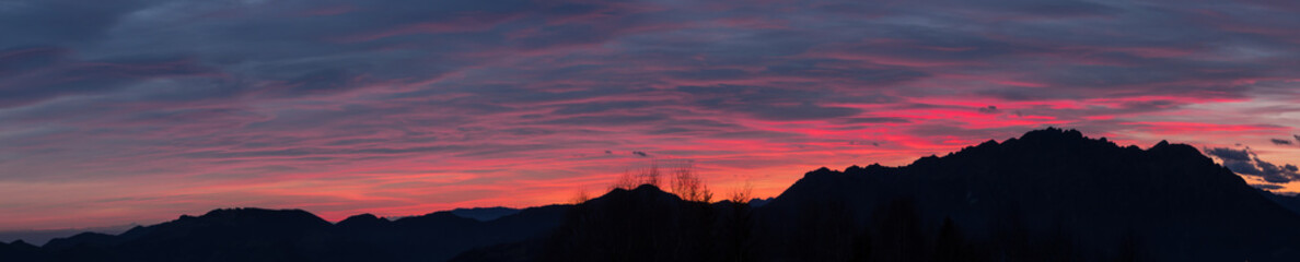 Fototapeta na wymiar Fiery sunset from mountain pick in a cloudy evening. Fall season. Orobie mountains. Italian Alps.