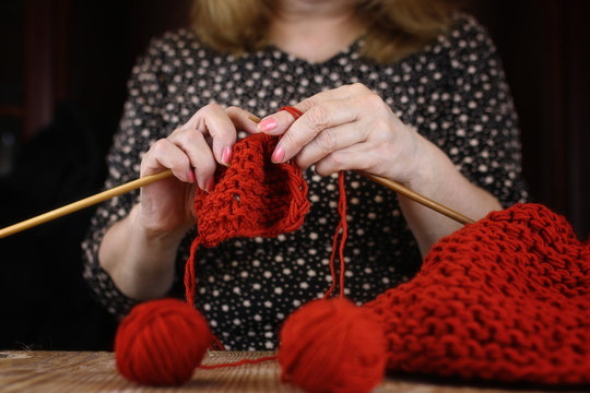 elderly woman is engaged in knitting warm sweaters for her grand