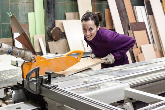 Women worker using saw machine to make furniture