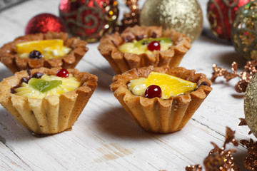 Homemade desserts with fruits for the new year. Desserts for the holidays. View from above. Christmas decorations and toys. The desserts on the wooden background.