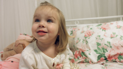 Adorable little girl sitting on a bed with her sister