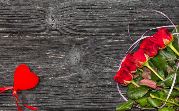 Red roses with red heart on black wooden background. Valentine's