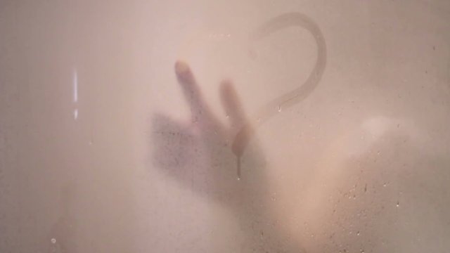 girl draws a heart on sweaty glass with your finger