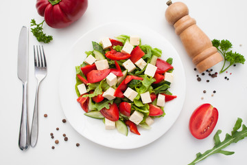 Restaurant serving of greek salad with cutlery flat lay. Top view on plate with side dish of fresh salad and feta cheese. Healthy food, vegetarian cuisine, menu, mediterranean meal concept