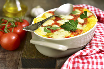 Polenta baked with tomato and cheese.