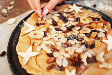 Decorating holiday pie with dry fruits close-up. Female hand preparing sweet treat for family, cooking process. Homemade bakery, valentines pastry, love, hobby, surprise concept