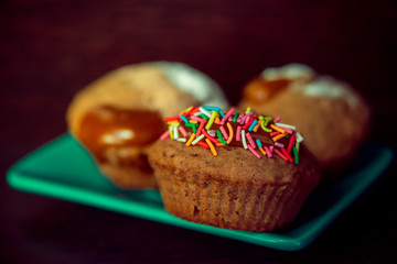 Домашние кексы на яркой тарелке на тёмном фоне 