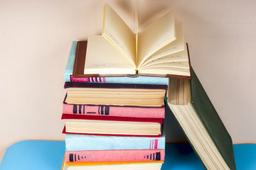 Open book, stack of colorful hardback books on light table. Back to school. Copy space for text