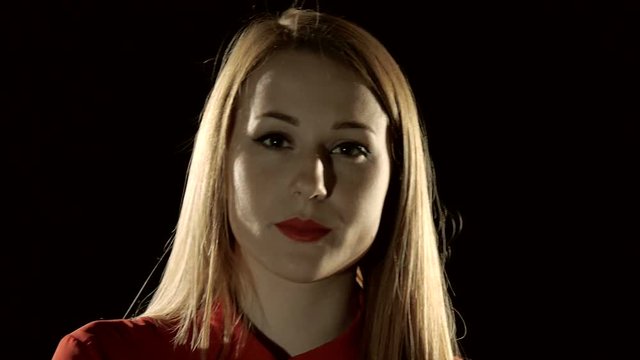 A young woman blond from a black background, emotion