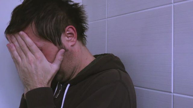 Depressed unhappy man crying lonely in bathroom