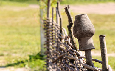 Old clay pot on a wicker fence made of sticks