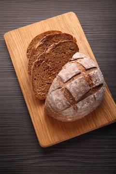 bread, cut on an oak board/ bread, cut on an oak board on a dark background
