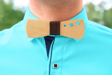 Best man in turquoise shirt with stylish wooden bow tie, close up