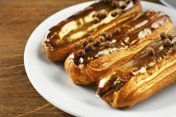 Delicious eclairs on wooden table closeup