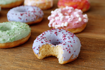 Tasty colorful donuts on wooden table, close up view