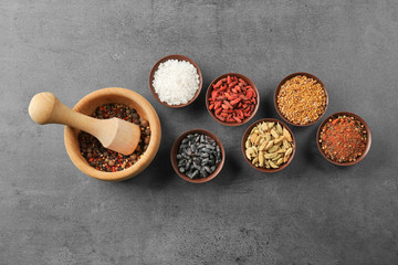 Composition with different spices and mortar on gray background