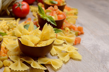 Different kinds of pasta on wooden background