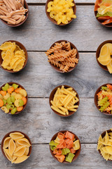 Different kinds of pasta in bowls on wooden background
