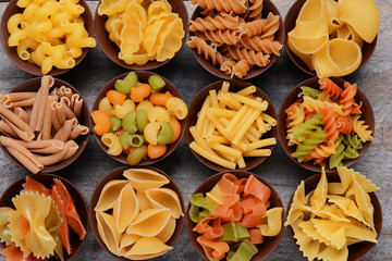 Different kinds of pasta in bowls on wooden background