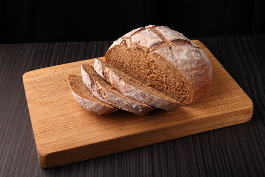 bread, cut on an oak board/ bread, cut on an oak board on a dark background