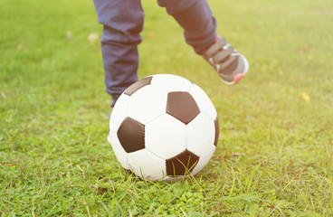 Close up view of boy's legs and ball on green grass
