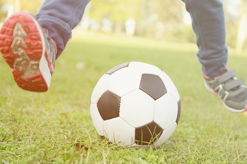 Close up view of boy's legs and ball on green grass