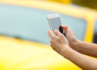 Woman ordering taxi by cellphone on blurred car background