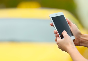 Woman ordering taxi by cellphone on blurred car background