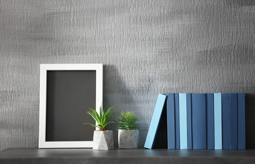 Books with frame on the table, on gray wall background