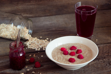 Oatmeal porridge with raspberries and compote on the wooden tabl