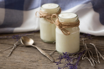 yogurt in jars on the wooden table with napkin, spoon and dried