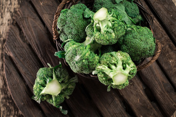 Fresh green broccoli in wood bowl over rustic wooden background
