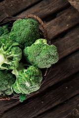 Fresh green broccoli in wood bowl over rustic wooden background