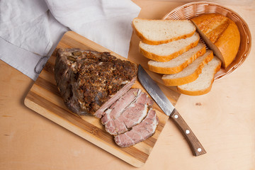 Baked pork with herbs and spice on wooden board and and slices w