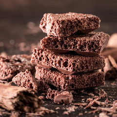 Porous chocolate in stack on a wooden background closeup.