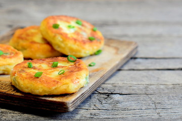 Homemade vegetable cutlets on a wooden board. Healthy cutlets made of potatoes, green peas, carrots and green beans and fried in a pan. Vegetarian dish. Rustic style. Closeup