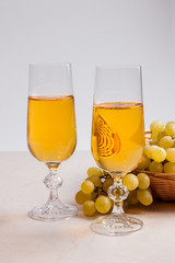 White wine and grapes. White wine in glasses and grapes on light