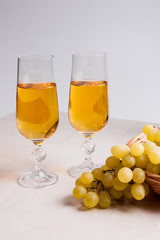 White wine and grapes. White wine in glasses and grapes on light