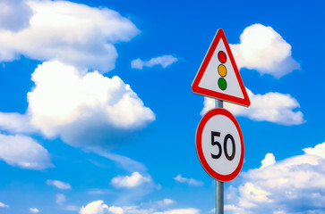 two road signs speed limit and traffic light on a background of blue sky and clouds
