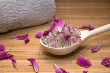 Fototapeta na wymiar homemade body scrub from sea salt and rose petals and peony pink towel on a straw Mat. Spa concept