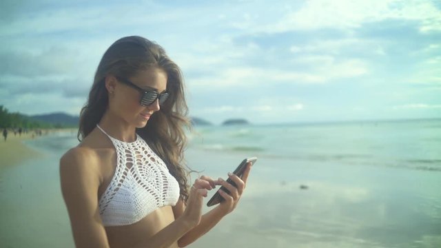 Woman Using Her Mobile Phone.On The Beach