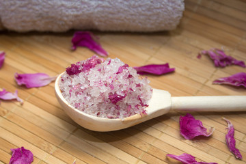 Obraz na płótnie Canvas homemade body scrub from sea salt and rose petals and peony pink towel on a straw Mat. Spa concept
