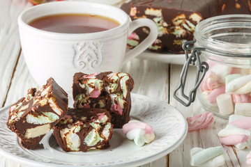 Chocolate bars with marshmallows and biscuits on a white wooden table. Rustic style. Selective focus
